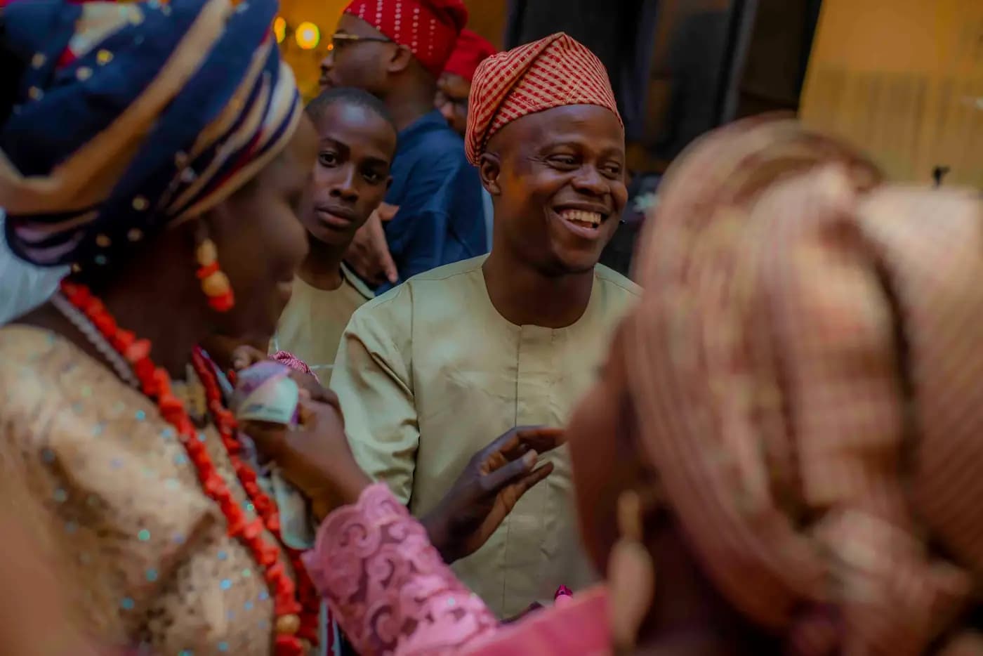 Guests in festive clothes, headwraps and boubous, laughing together at a wedding