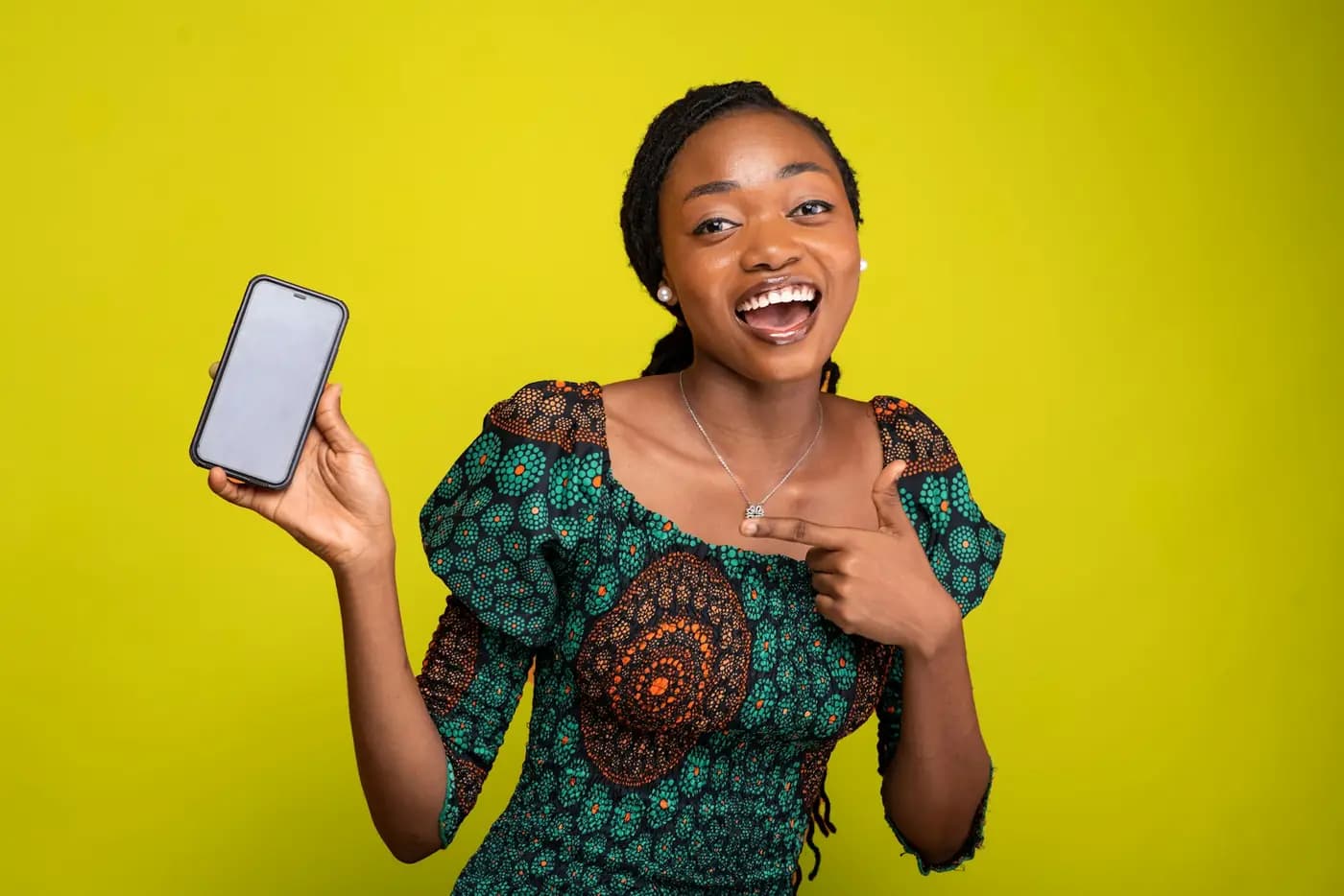 A guest in a wax print dress smiling and showing her phone